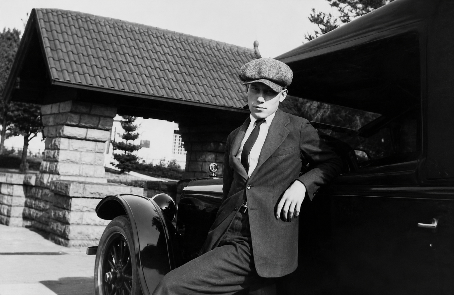 Vintage historical photo of man leaning on an old car